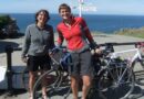 The couple with their bikes in front of a sign
