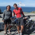 The couple with their bikes in front of a sign