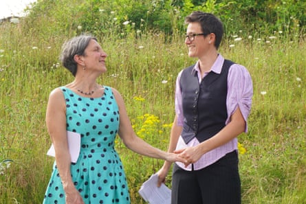 The couple holding hands in a field, while also holding printouts of their vows