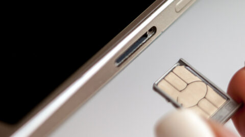 A SIM card being put into a smartphone using its tray.